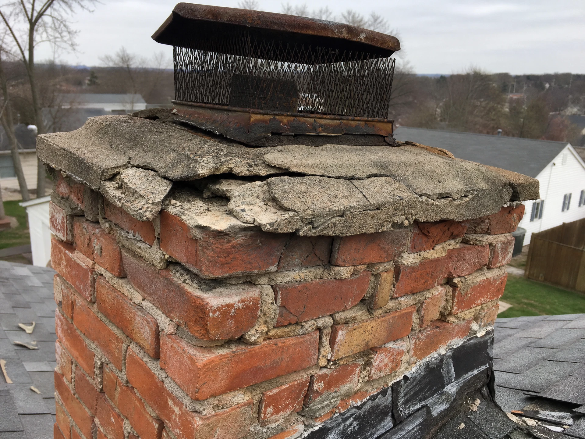 Cracked crumbling chimney crown and spalling brick before repair