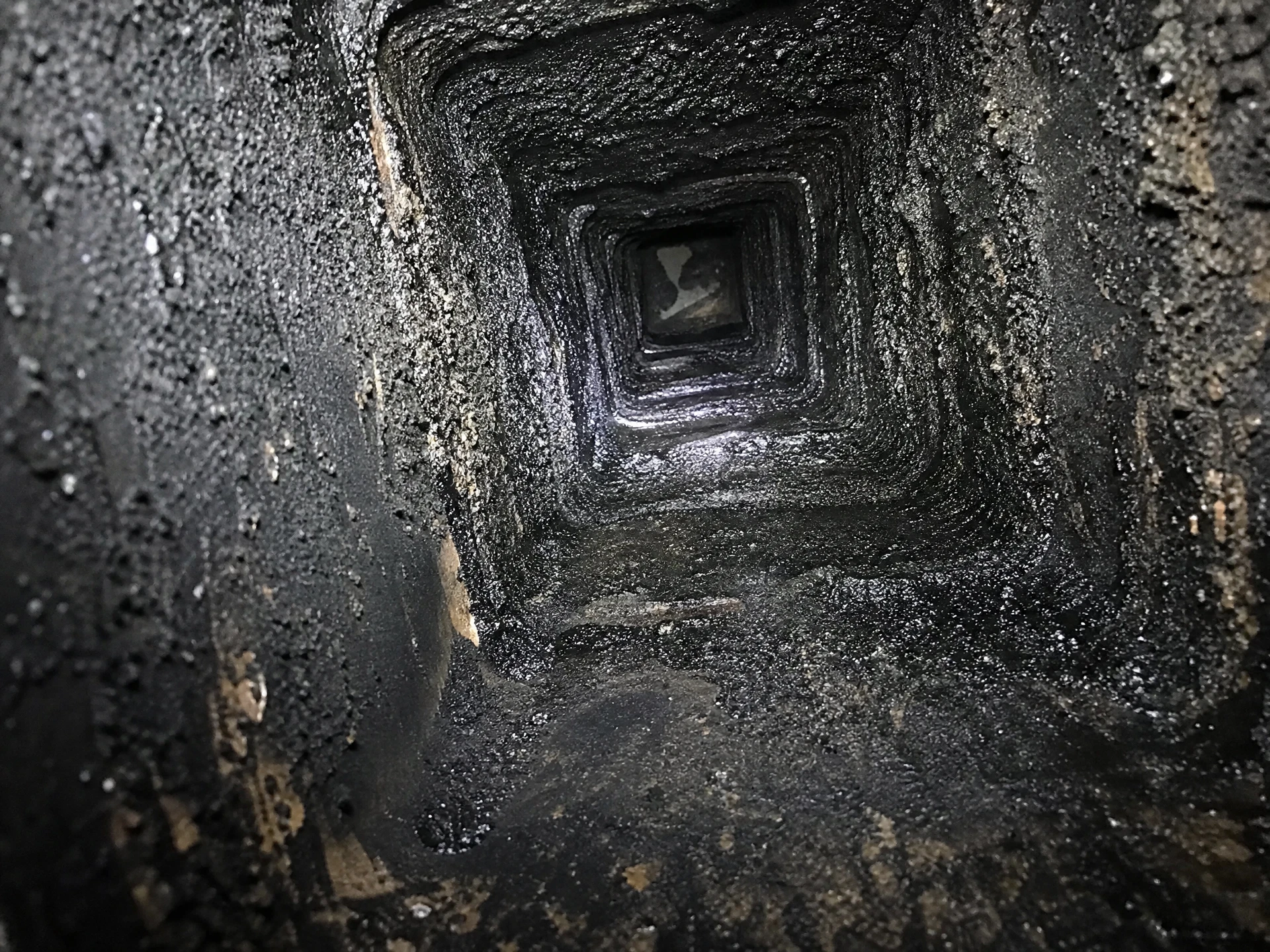 Chimney flue coated in dangerous glazed creosote before cleaning